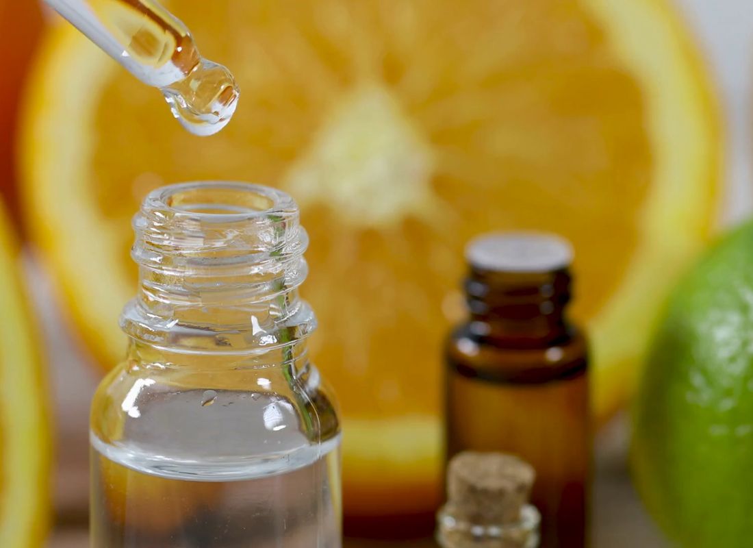 prikaz esencijalnih ulja i osobe koja sa pipetom uzima nekoliko kapi