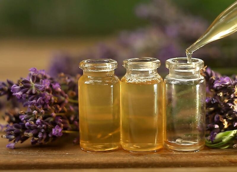 3 bočice lavande i lavanda u pozadini